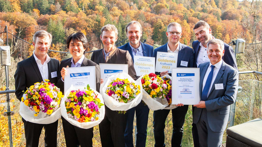Sieben Personen mit Urkunden und Blumensträuße